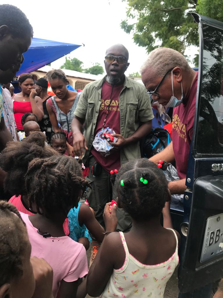 Group of Haitian people gathered around helpers from the non-profit Gayak Foundation.